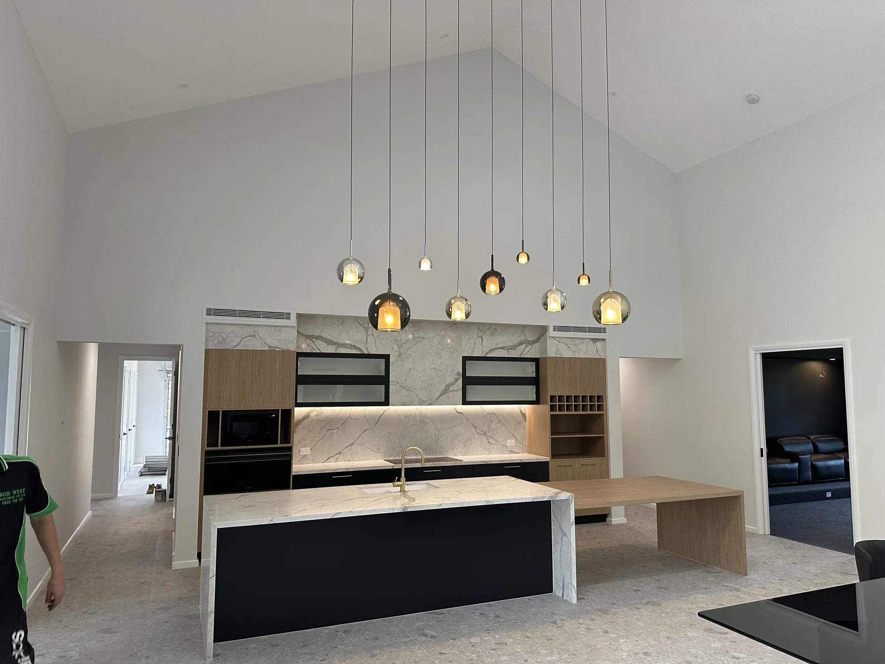 Pendant lighting above a kitchen island beneath a vaulted ceiling